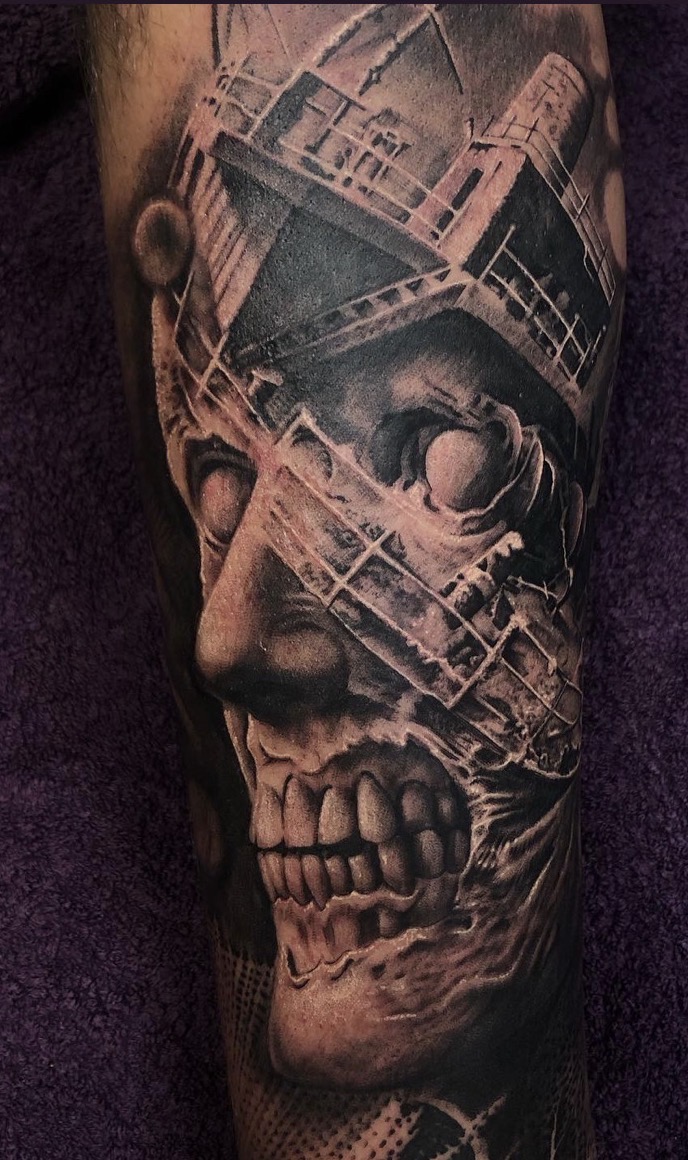 Düsteres Surrealismus- und Dark-Art-Tattoo in Black-and-Grey: Ein verfallenes, zombieförmiges Gesicht mit freigelegtem Gebiss, dessen Kopf surreal mit den Masten, Decks und Aufbauten eines versunkenen Schiffswracks verschmilzt.